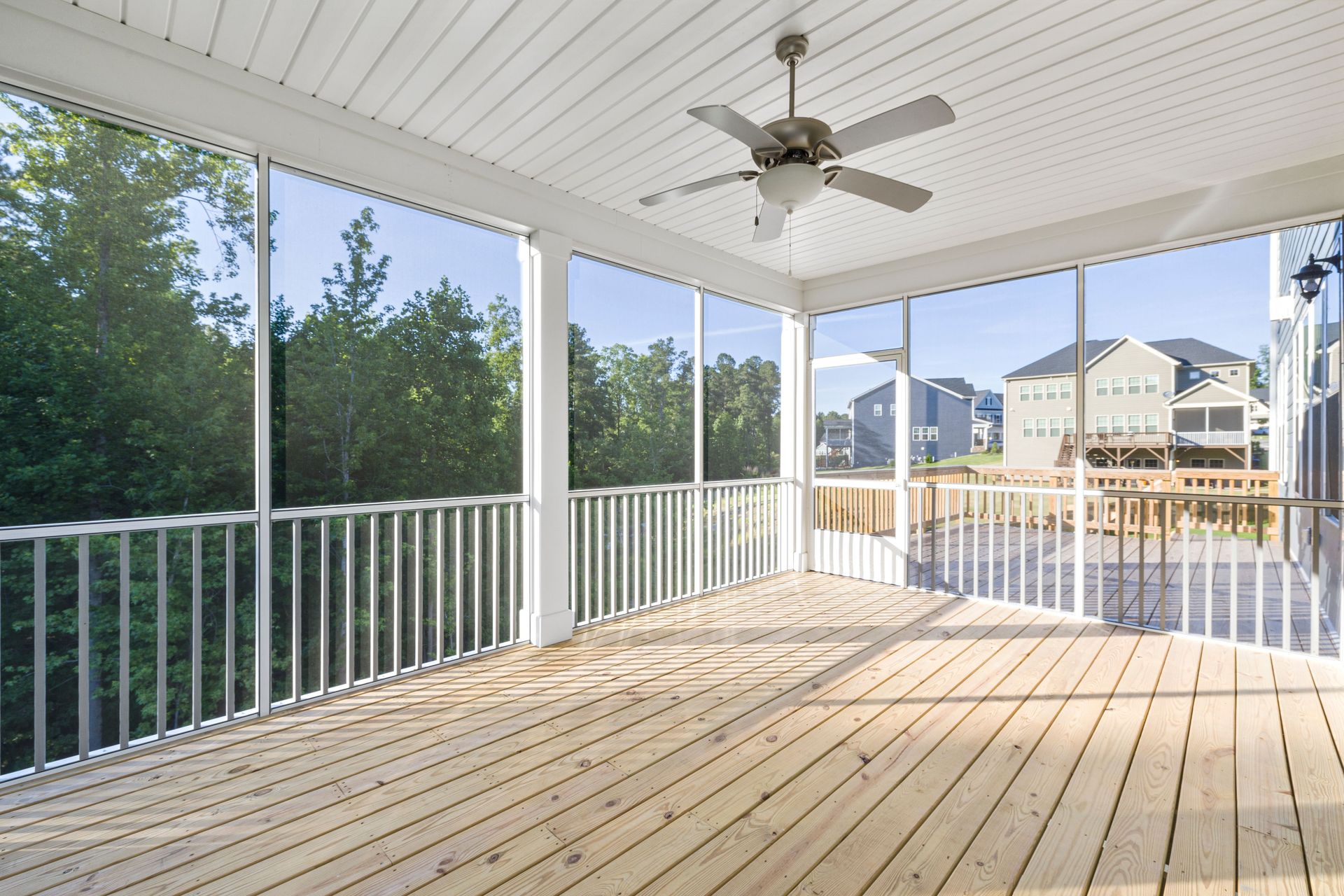 Bright and airy wooden porch with clear glass windows in a suburban setting.